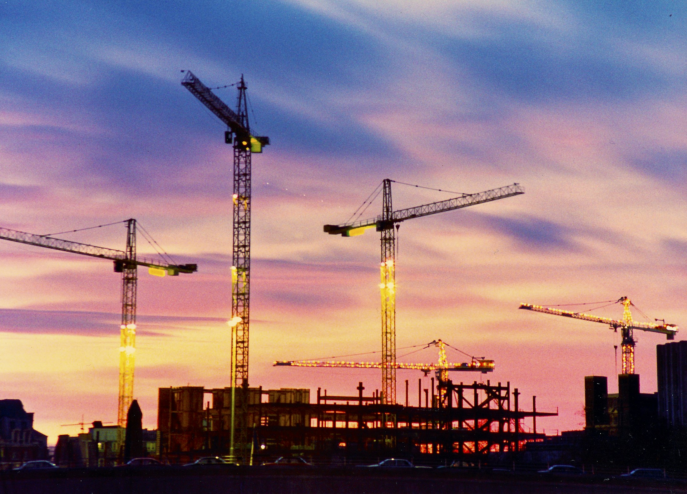 Tower cranes above a building under construction at dusk